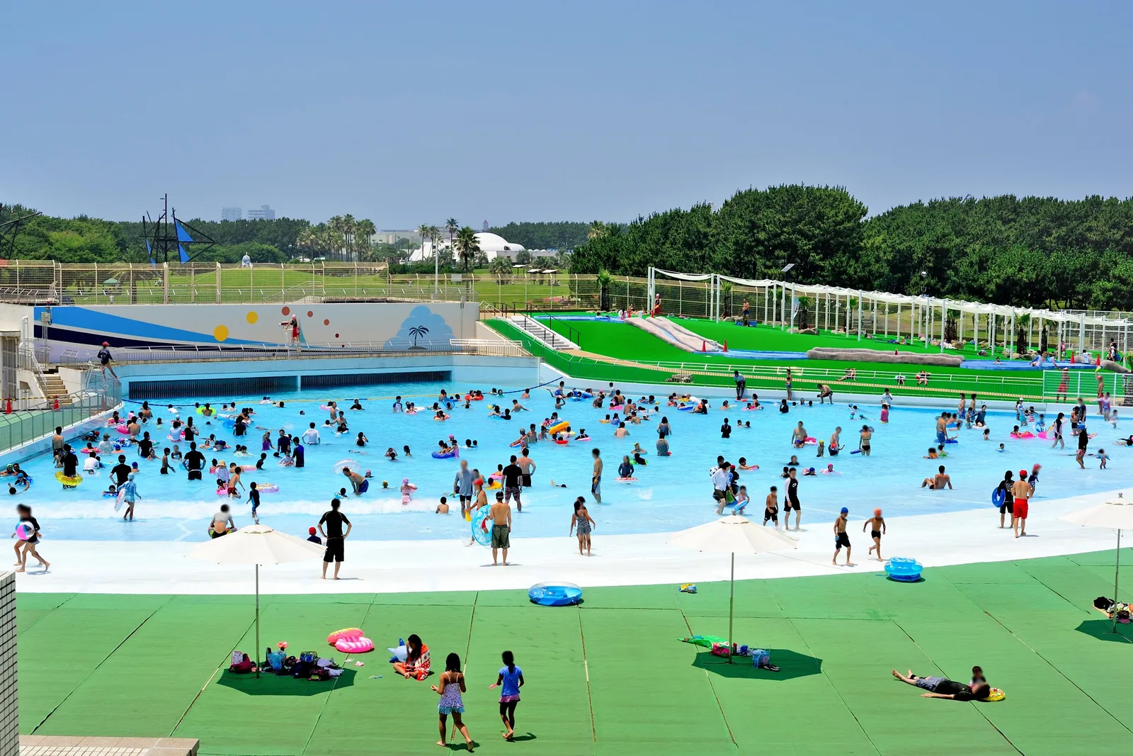 県立辻堂海浜公園のジャンボプール。利用者の顔をモザイク処理した波の出るプールの全景