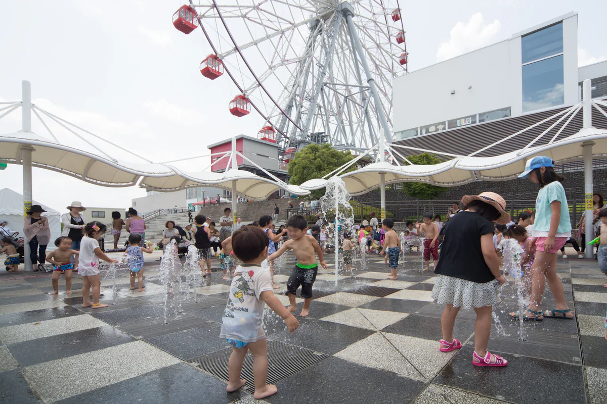 観覧車のそばにあるジャブジャブ・ミスト噴水で水遊びをする子どもたち。人物の顔はプライバシー保護のためぼかしています