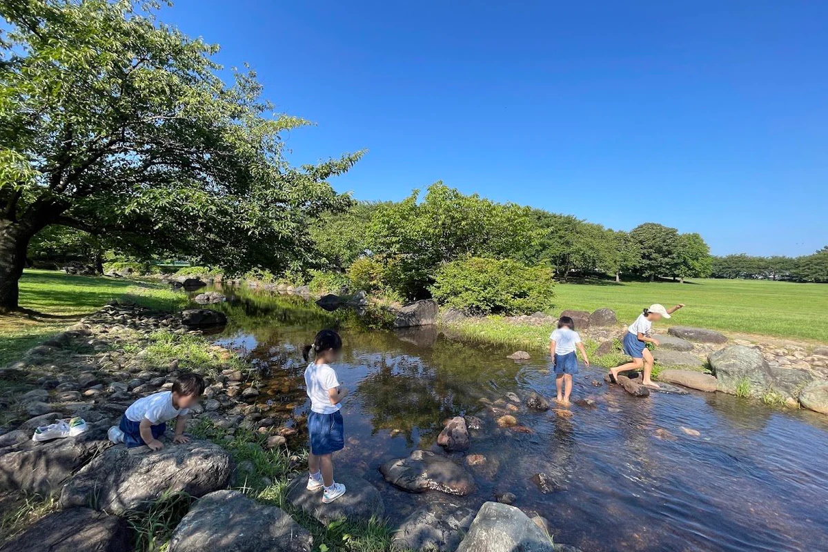 新潟県スポーツ公園のレストハウス前・遊具広場近くにある浅い「流れ」で水遊びをする子どもたち。人物の顔はプライバシー保護のためぼかしています