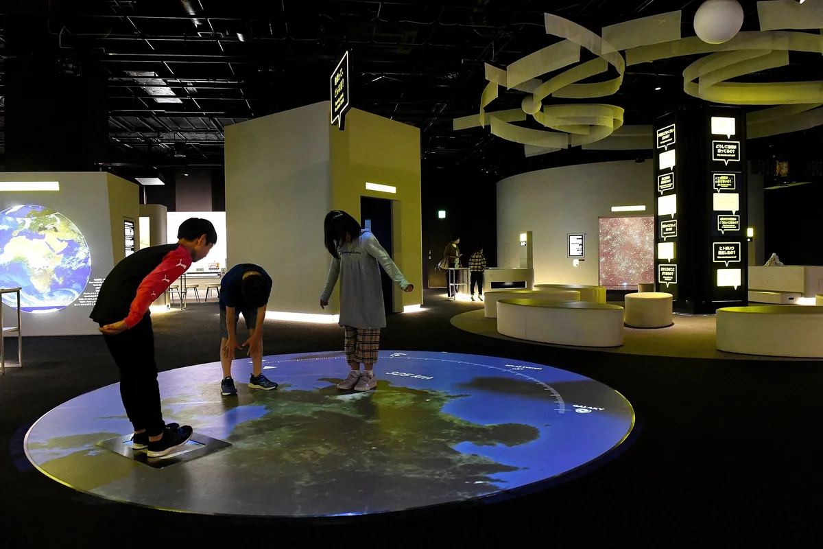 福岡市科学館5階基本展示室で床面に投映された地球の展示を体験する子どもたち