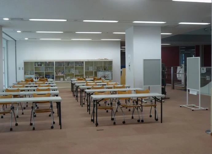 こむこむ館2階交流コーナー。机と椅子が並ぶ明るい室内